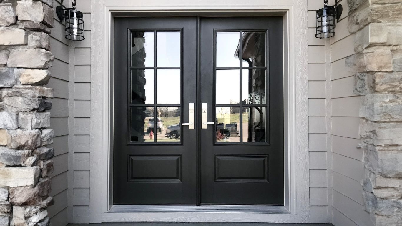 Elegant double front doors with glass panels, set against a stone and siding entryway, showcasing modern design ideal for remodeling projects.