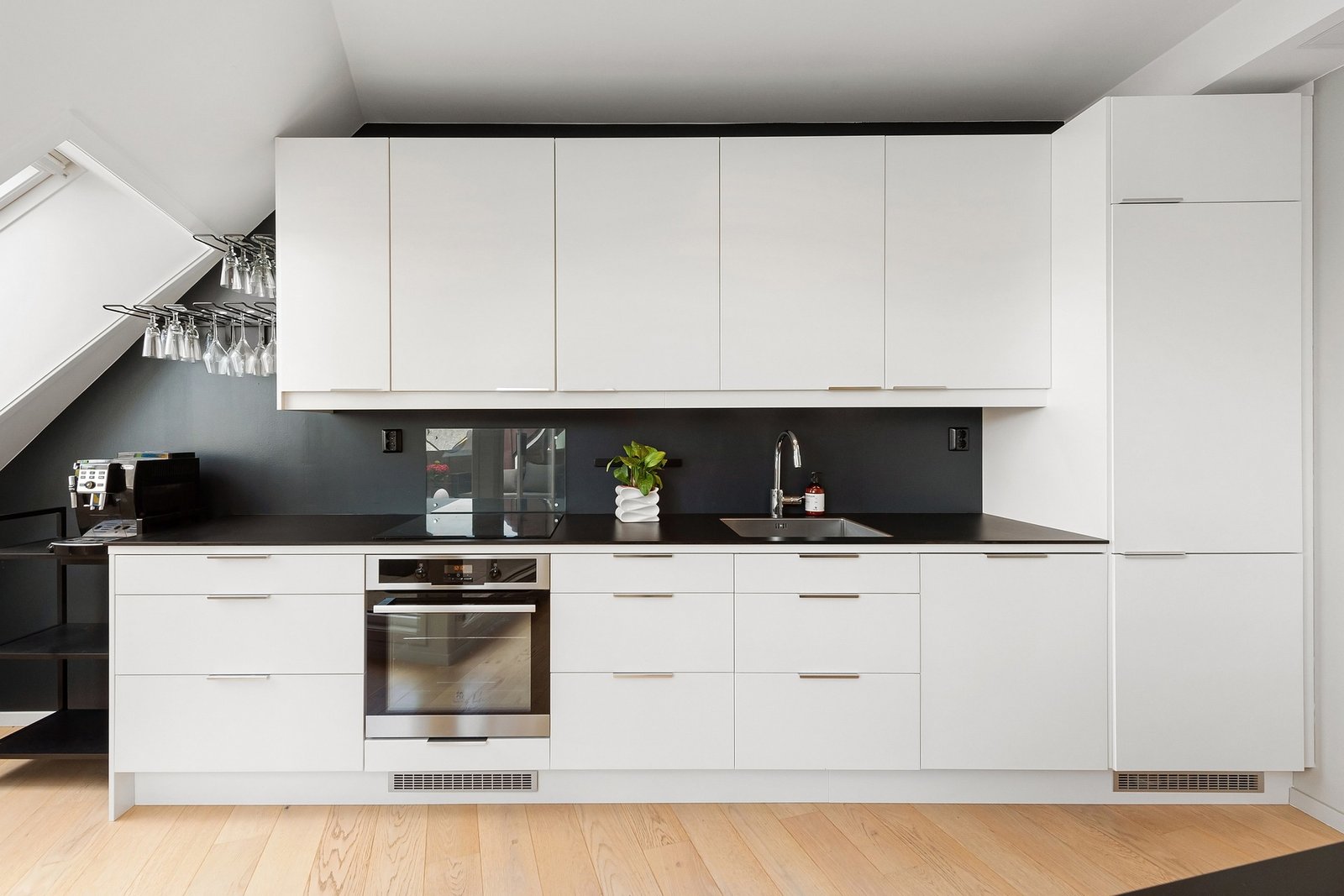 Modern kitchen with sleek white cabinetry, black countertops, and built-in appliances. Duluth Construction specializes in kitchen remodels, custom carpentry, and home remodeling to enhance functionality and style.