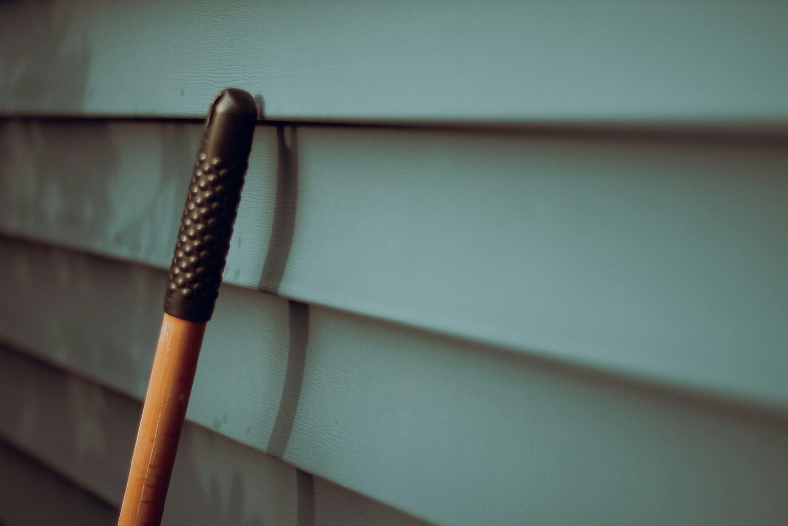 Close-up of a home’s exterior siding with a repair tool in focus. Duluth Construction specializes in high-quality siding installation and repair services.