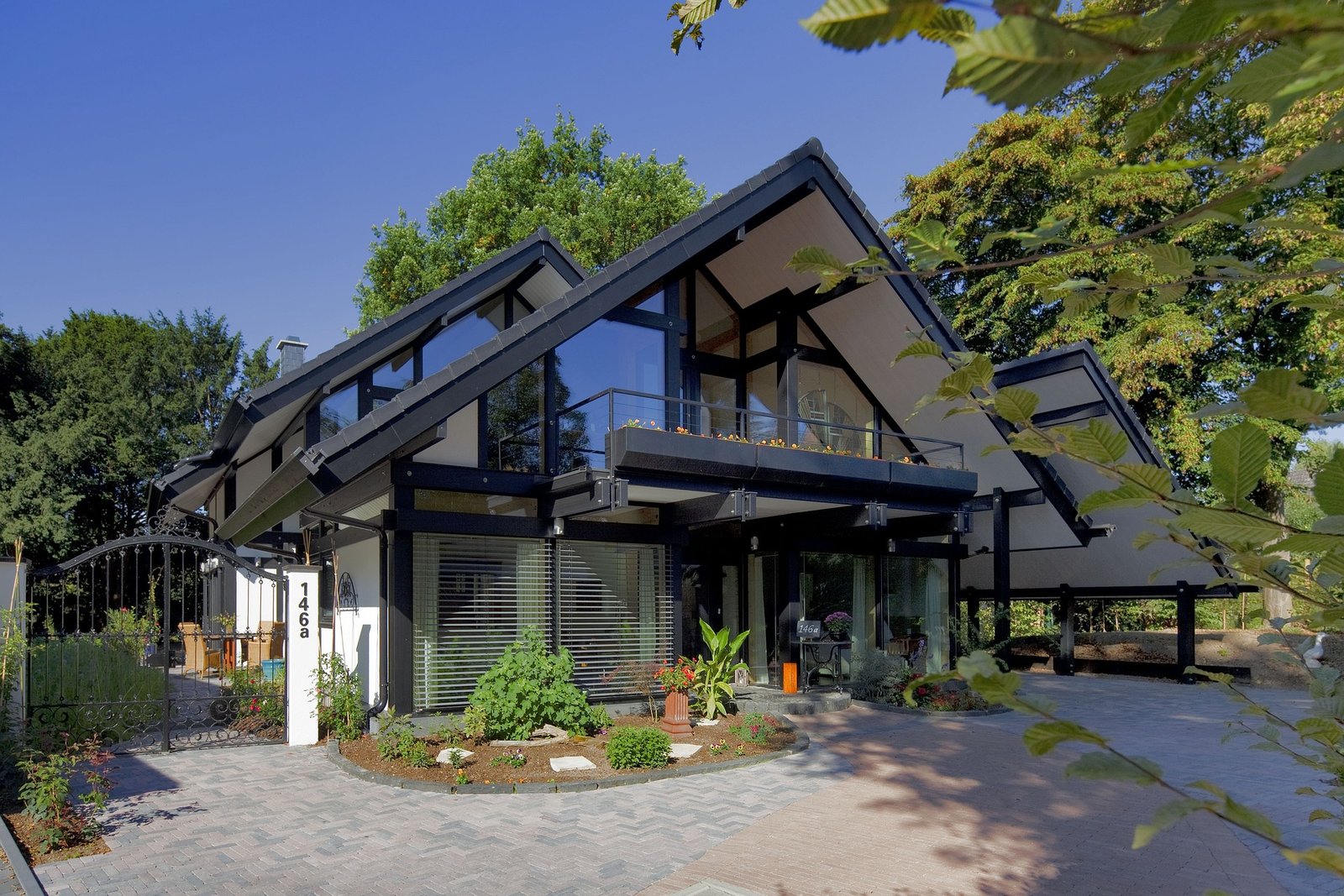 Modern home with black-framed glass architecture, expertly designed by Duluth Construction, featuring sleek lines, a spacious balcony, and a beautifully landscaped entrance.