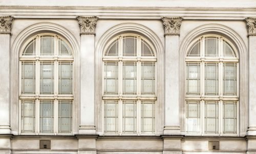 Elegant arched windows with intricate detailing, showcasing custom window solutions by Duluth Construction for historic and modern buildings.