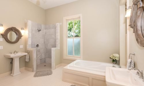 Elegant bathroom remodel by Duluth Construction featuring a spacious walk-in shower with marble tile, a built-in bathtub, and modern plumbing fixtures.