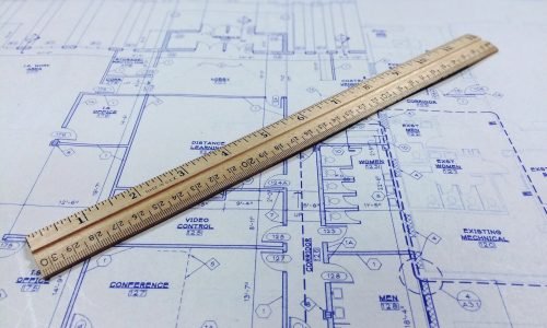 Architectural blueprint with a wooden ruler placed on top, representing custom carpentry, home remodelers, and framing near me services by Duluth Construction for high-quality home building and renovations.