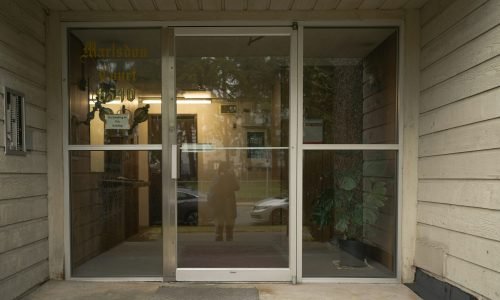 Commercial glass entry door with aluminum framing, reflecting the surrounding environment. Duluth Construction specializes in high-quality door installation, repair, and replacement services for residential and commercial properties, ensuring durability and modern aesthetics.