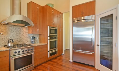 Modern kitchen with stainless steel appliances, custom wood cabinetry, and granite countertops by Duluth Construction. Elegant and functional design.