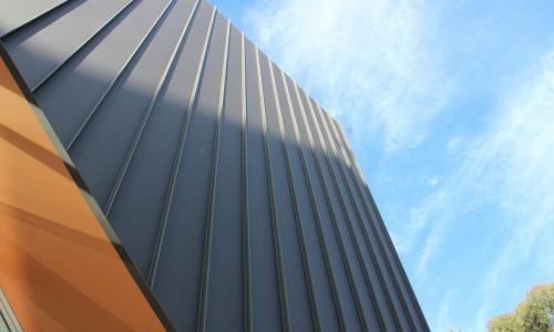 Close-up of modern metal siding with vertical paneling on a contemporary building, highlighting durability and sleek design. Duluth Construction offers expert metal siding installation for residential and commercial properties.