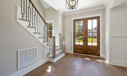 Elegant entryway featuring custom wooden double doors with glass panels, allowing natural light to brighten the space. Duluth Construction specializes in high-quality custom entry doors, interior door installation, and expert craftsmanship for modern and classic home designs.