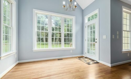 Bright sunroom with large energy-efficient windows and French door installation by Duluth Construction, enhancing natural light and home value.