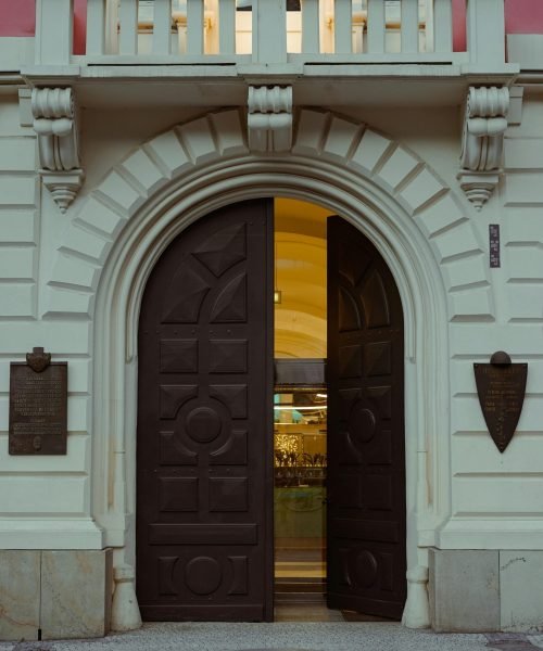 Elegant arched double doors with intricate wood paneling in a historic building entrance. Duluth Construction specializes in custom entry doors, door replacement, and high-quality craftsmanship for residential and commercial properties.