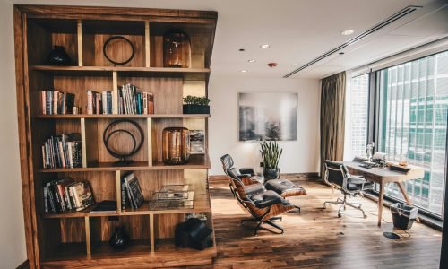 Modern home office with custom-built wooden bookshelves, elegant hardwood flooring, and a stylish workspace overlooking a cityscape. Duluth Construction specializes in custom carpentry, cabinetry installations, and high-end interior remodeling to enhance your living and working spaces.