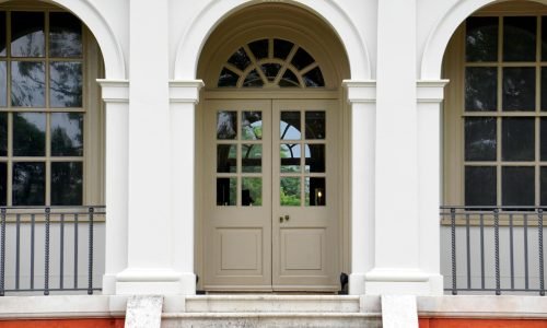 Elegant double entry doors with glass paneling and an arched transom window, enhancing the classic architecture. Duluth Construction specializes in custom entry door installation, repair, and replacement, providing high-quality craftsmanship for residential and commercial properties.