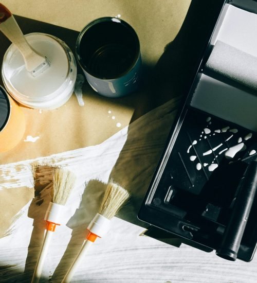 Painting supplies, including brushes, paint cans, and a roller tray, set up for an interior painting project. Duluth Construction provides expert painting services for residential and commercial spaces, ensuring high-quality finishes.