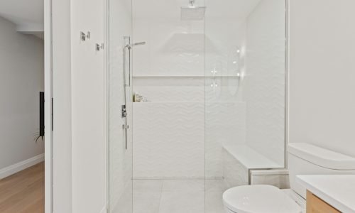 Modern bathroom with a sleek glass shower enclosure, rainfall showerhead, and elegant white tile design. Duluth Construction specializes in high-quality bathroom renovations, custom shower installations, and premium finishes for a luxurious and functional space.