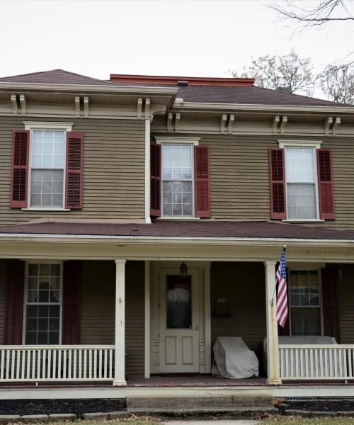 Historic two-story home with wood siding and red shutters. Duluth Construction provides expert wood siding installation and repair services to preserve the charm and durability of classic homes.