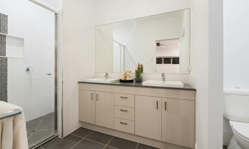 Modern bathroom renovation by Duluth Construction featuring a sleek double vanity with a large mirror, spacious walk-in shower, and stylish tile flooring.