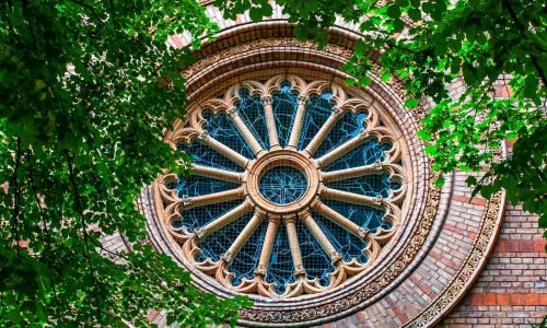 Intricately designed circular stained glass window with ornate brick detailing, showcasing expert window repair and restoration by Duluth Construction.